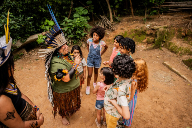 Indigenous woman talking with children during a field trip to village