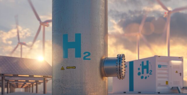 Hydrogen energy storage gas tank with solar panels, wind turbine and energy storage container unit in background at sunset
